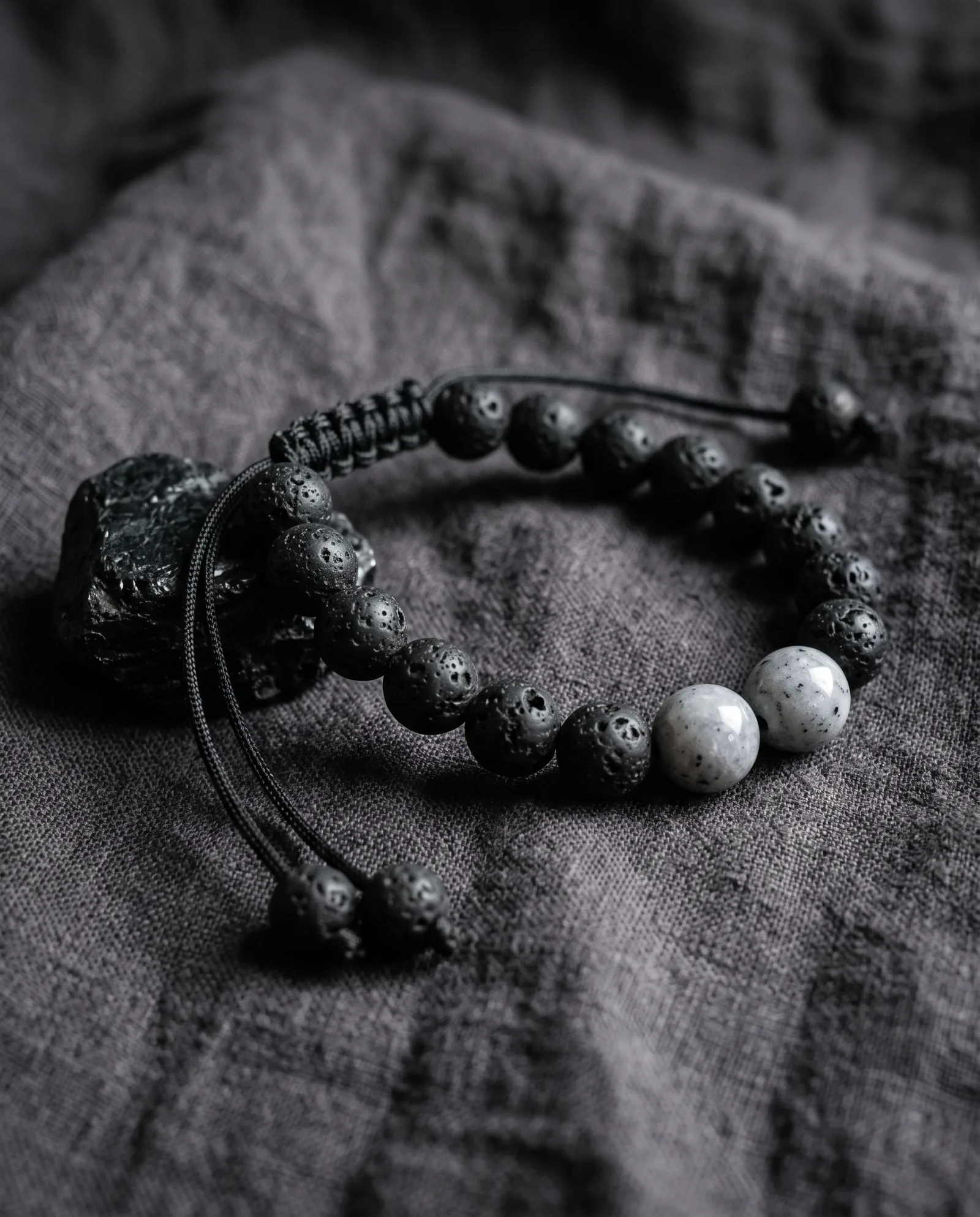 Bracelet en perles de lave noire mate et deux perles pâles mouchetées